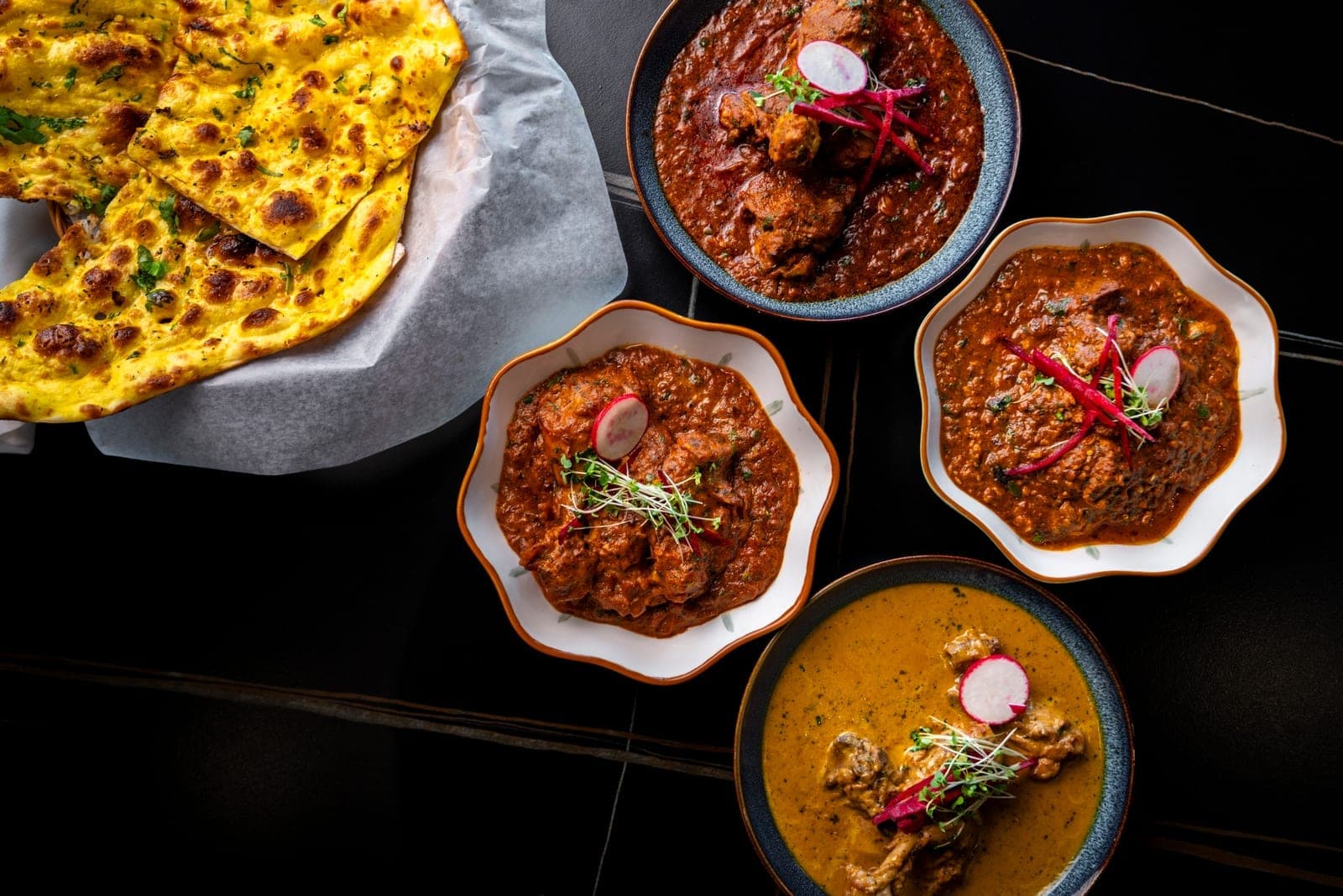 Overhead spread of curries, naan and tandoori at DesINorth Milton, Ontario, Canada